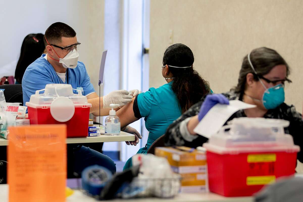 Registered Nurse Devin Perez (left) administers the Moderna vaccine to a Alameda County essential worker while at St. Rose Hospital in Oakland, Calif. Friday, January 8, 2021. Hundreds of Alameda County workers lined up outside of St. Rose Hospital to receive their first and second doses of the Pfizer and Moderna vaccines after being invited to make an appointment through their workplaces.
