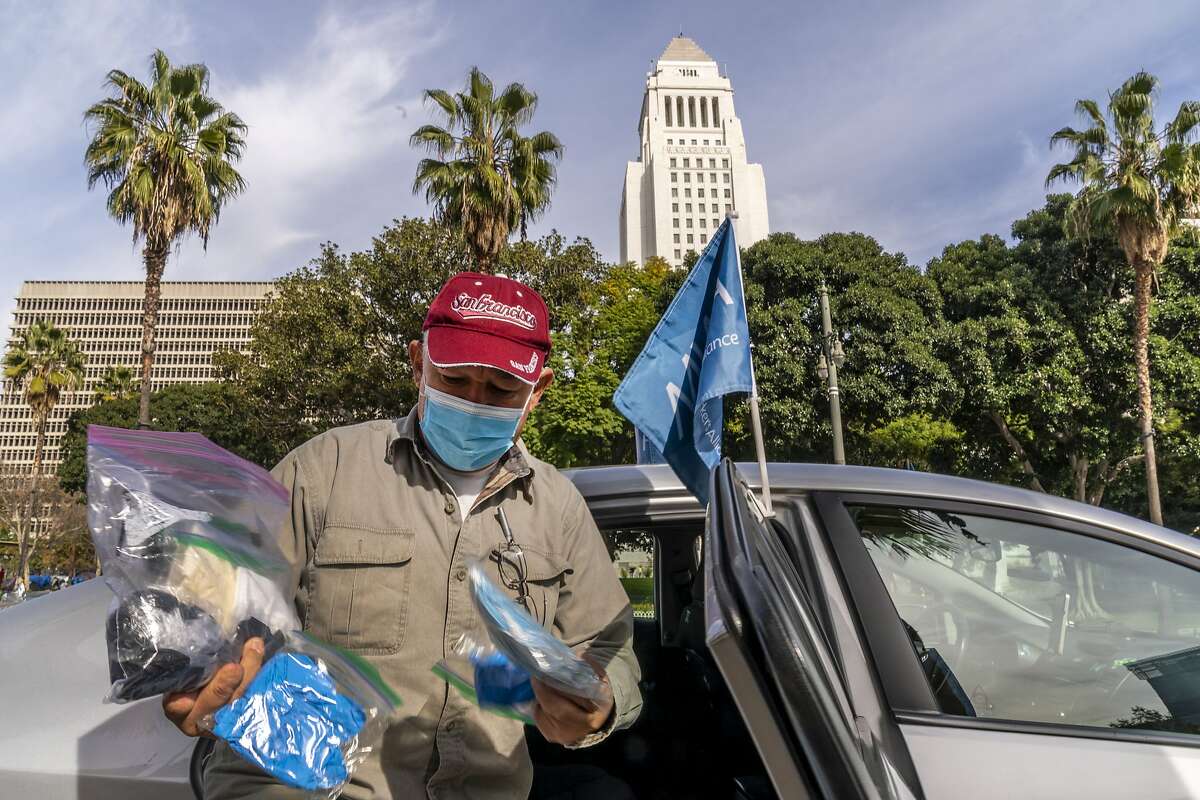 Uber driver Jose Luis Guevara, a member of the Mobile Workers Alliance, shows personal protective equipment, he provides to ride-sharing customers. Some drivers for app-based ride-hailing and delivery services are suing to overturn a California ballot initiative that makes them independent contractors instead of employees.