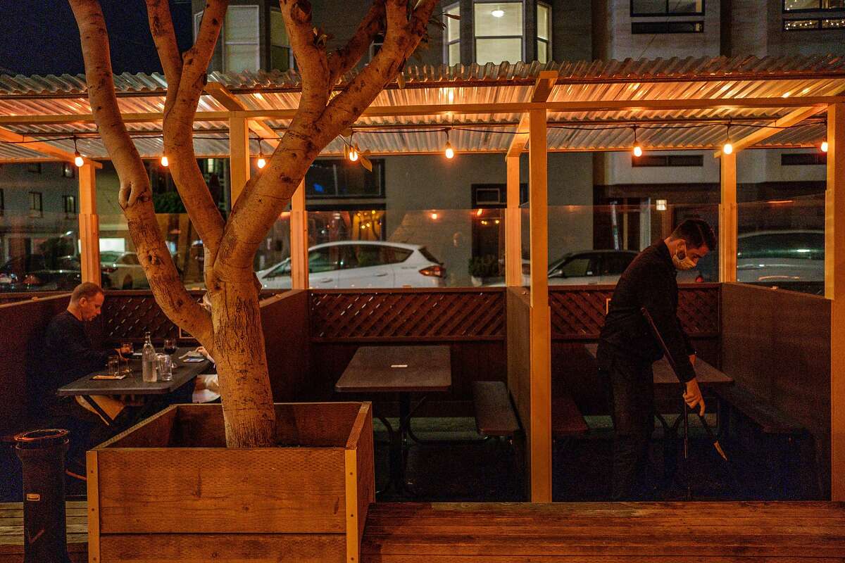 Ronnie Selak sweeps the parklet at Brazen Head in San Francisco.