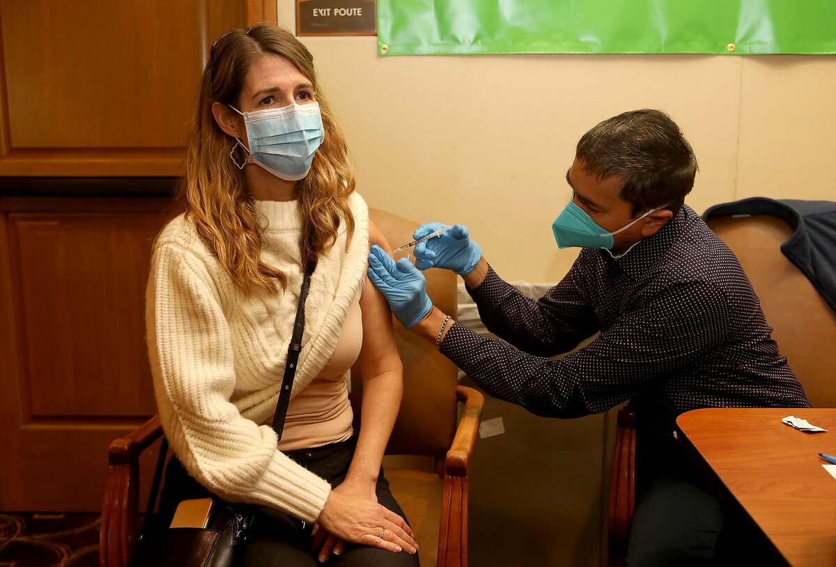 Emily Tait receives the Pfizer COVID-19 vaccination from CVS pharmacist Sanjay Patel in Pleasanton.