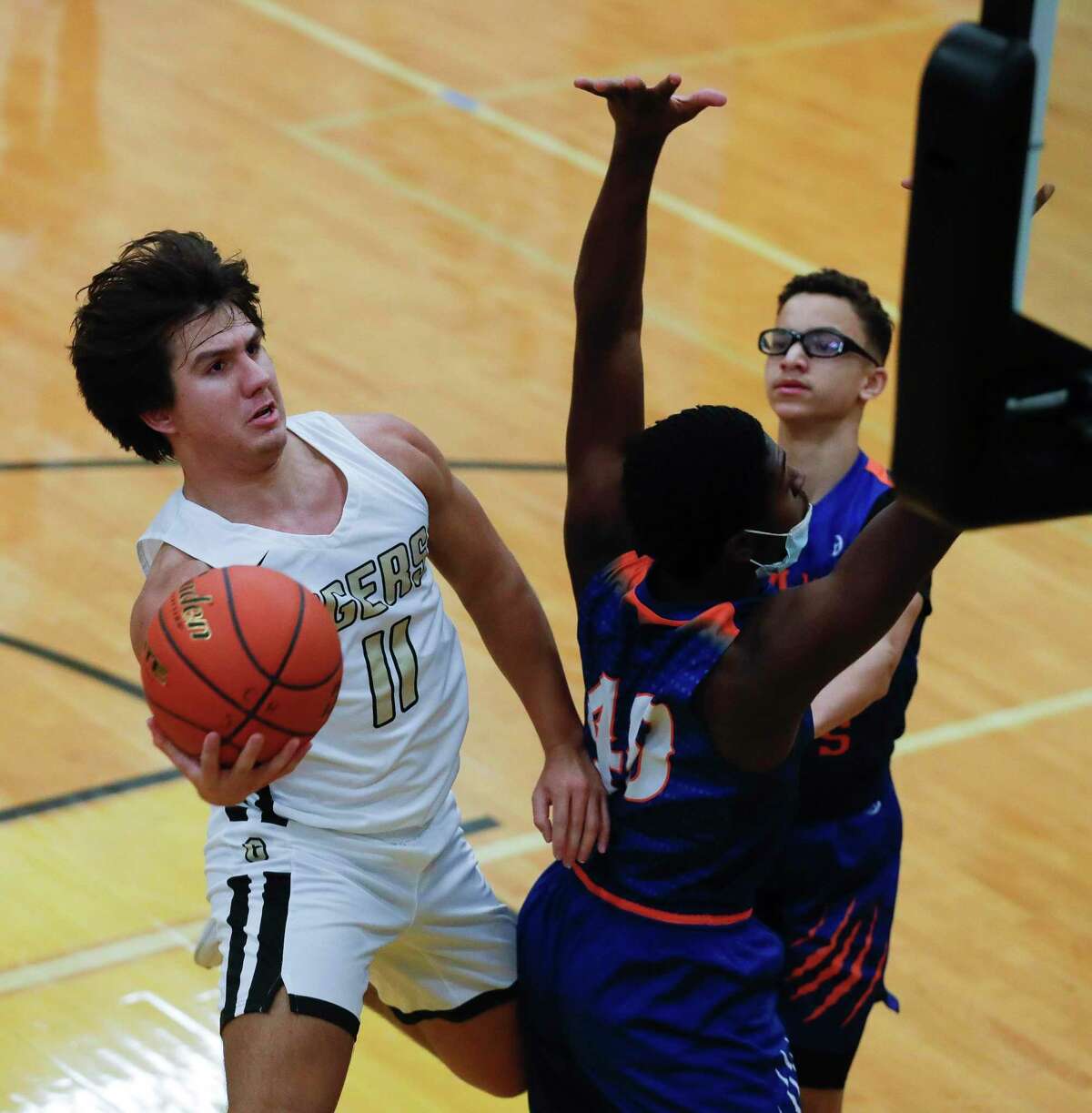 Conroe’s Layne O’Dell (11) scoops the ball around Grand Oaks’ Ahmad Smith (40) during the first quarter of a District 13-6A high school basketball game at Conroe High School, Wednesday, Jan. 13, 2021, in Conroe.