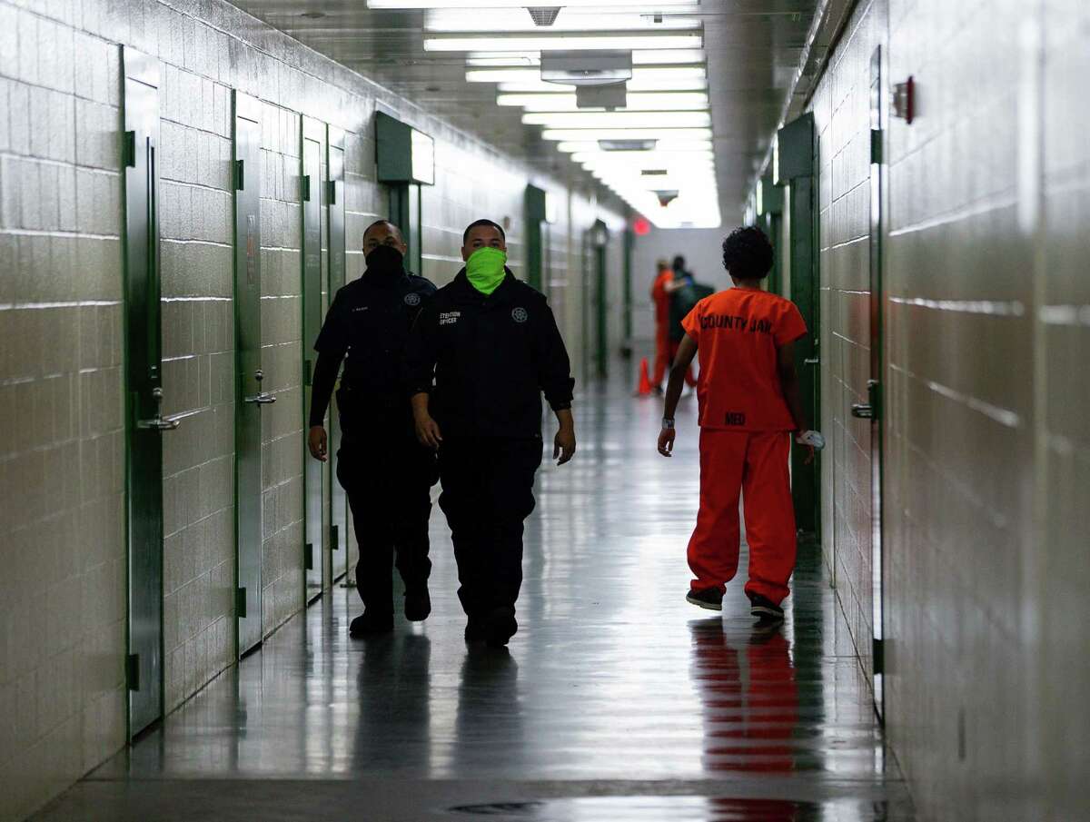 Harris County Sheriff's Office deputies walk past an inmate inside the detention facility on Thursday, Jan. 14, 2021, in Houston.