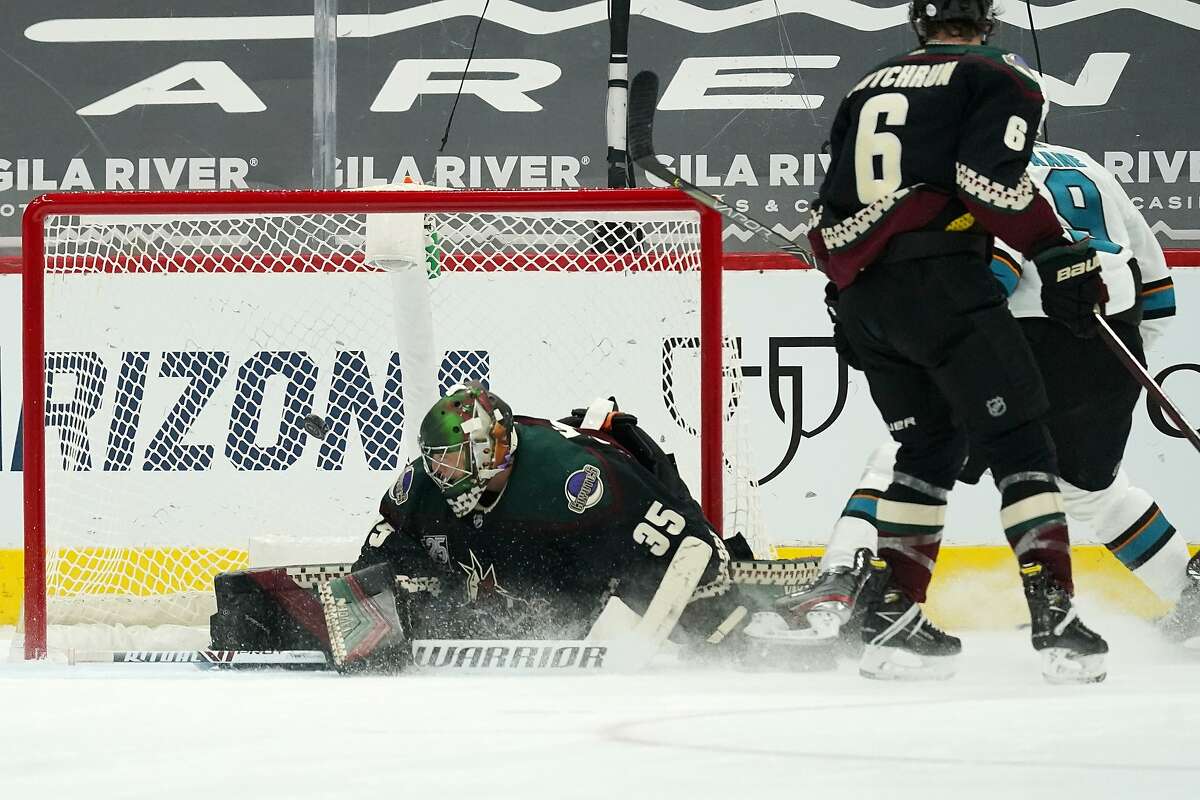 San Jose Sharks left wing Evander Kane, back right, scores a goal against Arizona Coyotes goaltender Darcy Kuemper (35) as Coyotes defenseman Jakob Chychrun (6) watches during the third period of an NHL hockey game Thursday, Jan. 14, 2021, in Glendale, Ariz. The Sharks won 4-3 in a shootout. (AP Photo/Ross D. Franklin)