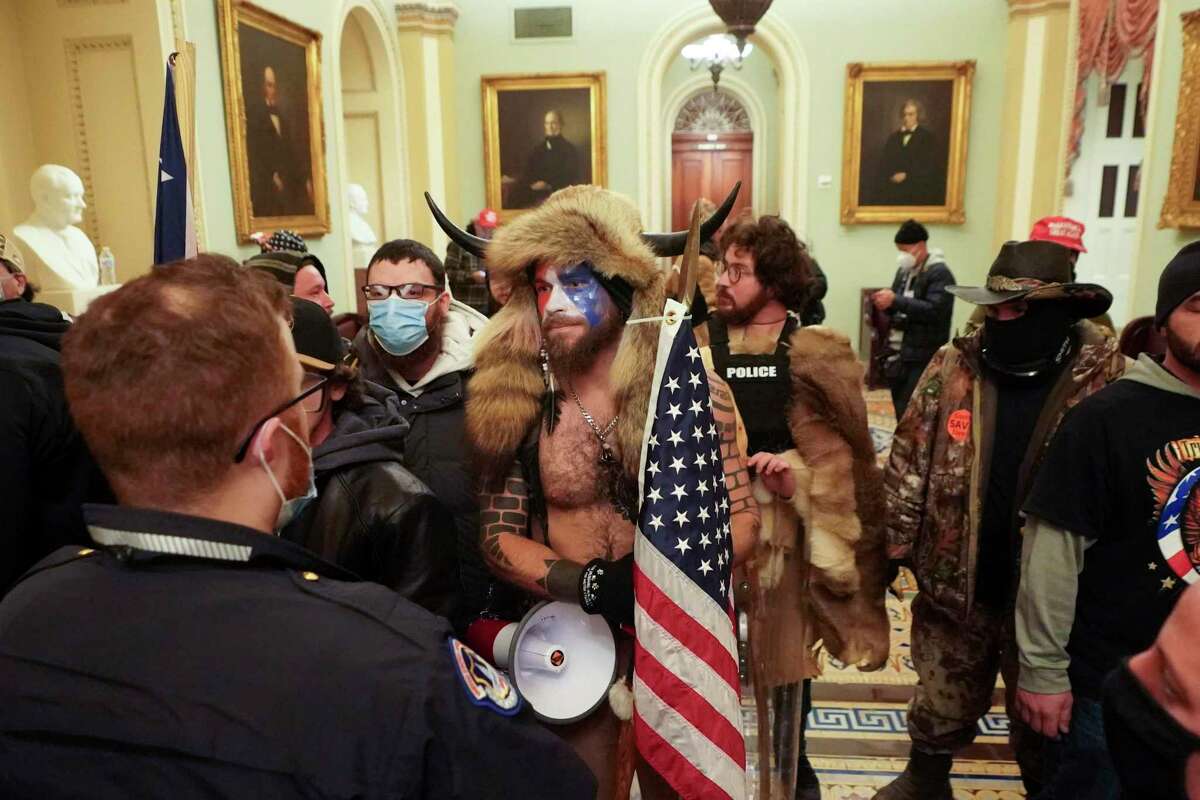 Jake Angeli, center, a QAnon adherent known as the Q Shaman, pictured here with other insurrectionists at the U.S. Capitol. Do Republicans really want to be associated with this guy?
