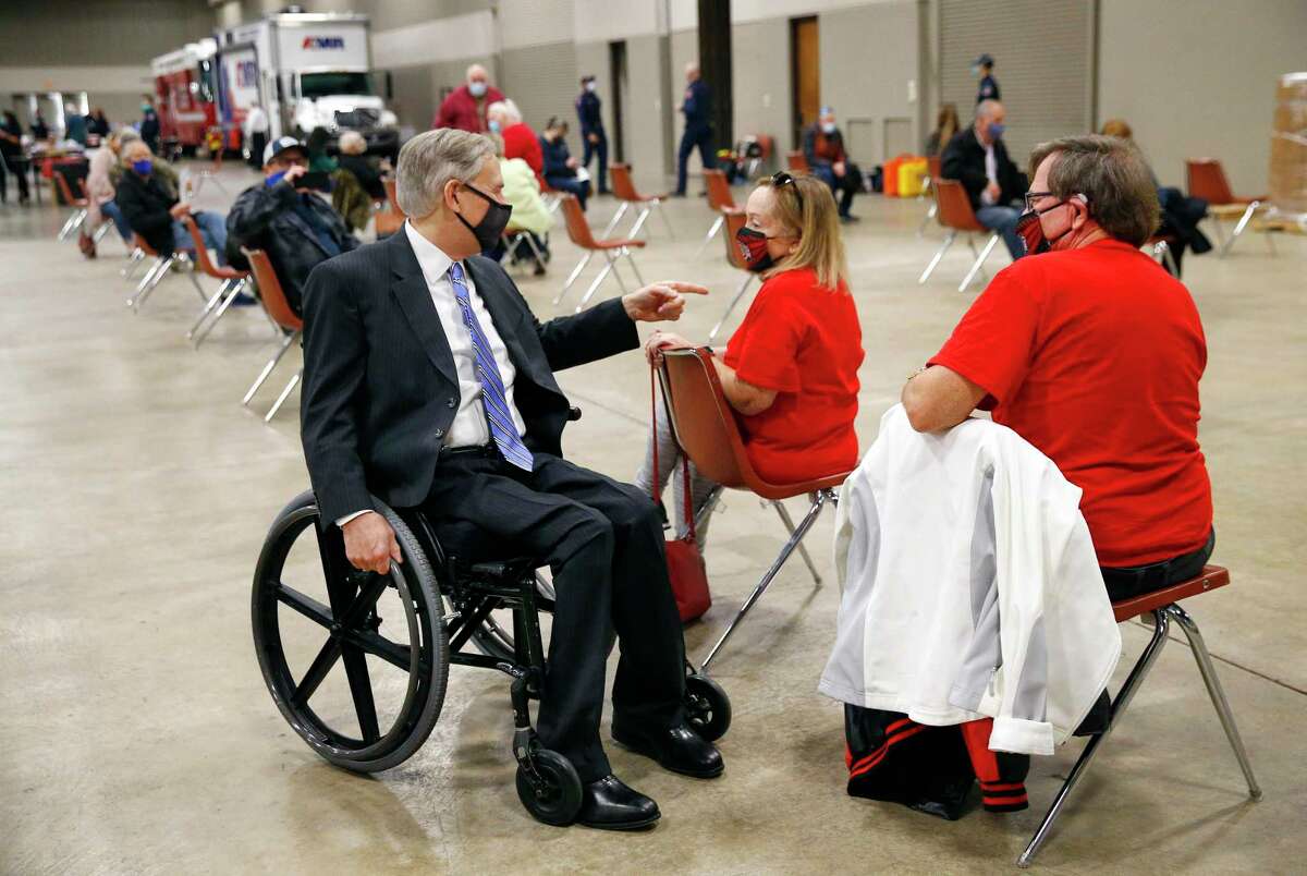 Texas Governor Greg Abbott (left visits with Michael and Sara Cramer of Arlington in a waiting area after receiving their COVID-19 shots at a mass COVID-19 vaccination site at the Esports Stadium Arlington & Expo Center in Arlington, Texas, Monday, January 11, 2021. (Pool/Tom Fox/The Dallas Morning News)