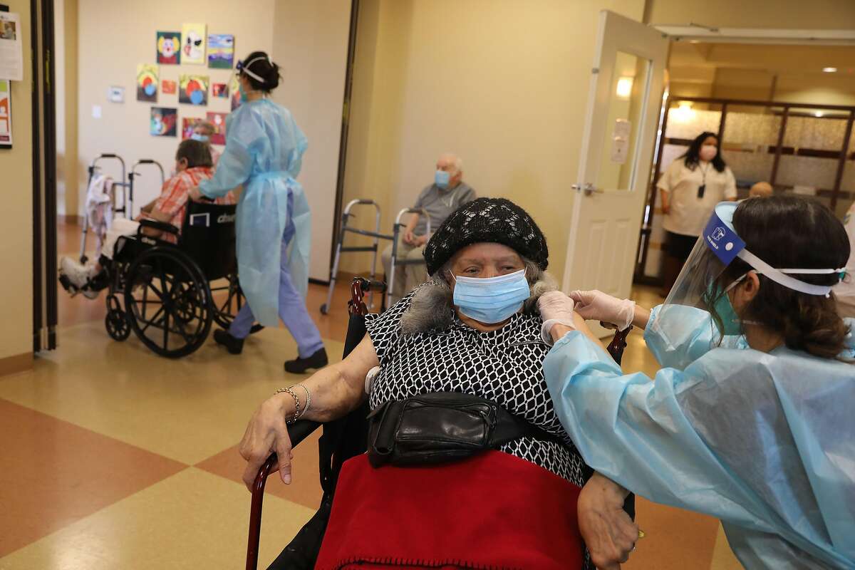 CVS nurse Casey Domine gives the Pfizer COVID-19 vaccine to Norma Paglinawan, 93, at the Peninsula Del Rey vaccine clinic in Daly City.