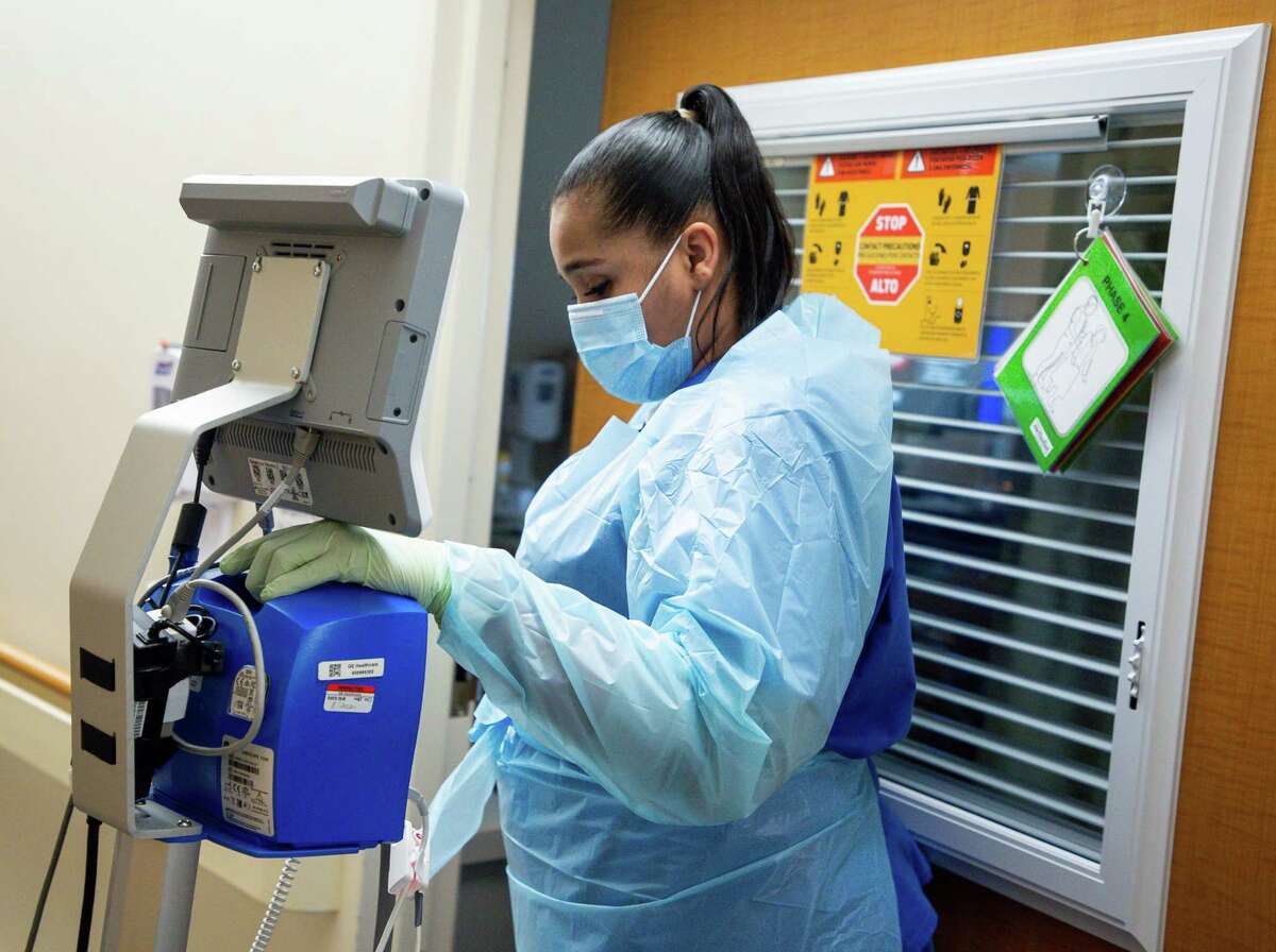 Darrelyn Mathieu, patient care assistant, enters a patient's room in the cardiovascular acute care unit, at Houston Methodist Debakey Heart and Vascular Center on Thursday, Jan. 14, 2021, in Houston. Texas hospitals, already facing an increase in patients brought by the pandemic, is dealing with poached nurses. Seven months after hospitals competed for ventilators, personal protective equipment and COVID-19 test, nurses have become the hot commodity, desperately needed around the country.