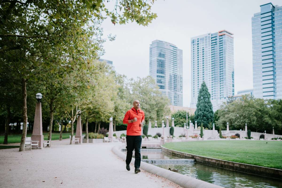 A man goes for a morning run through Bellevue's Downtown Park, a perfect place for a jog or other exercise with open footpaths and city skyline views.