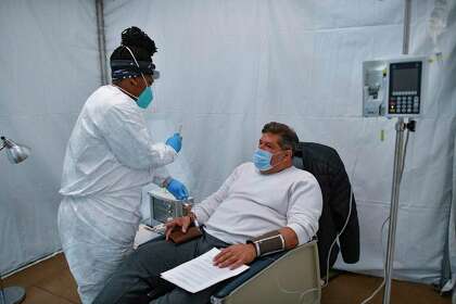 COVID-19 patient Roger Machina is checked by nurse Kizzie Shipman during an antibody infusion at the Freeman Coliseum complex on Friday, Jan. 15, 2021.