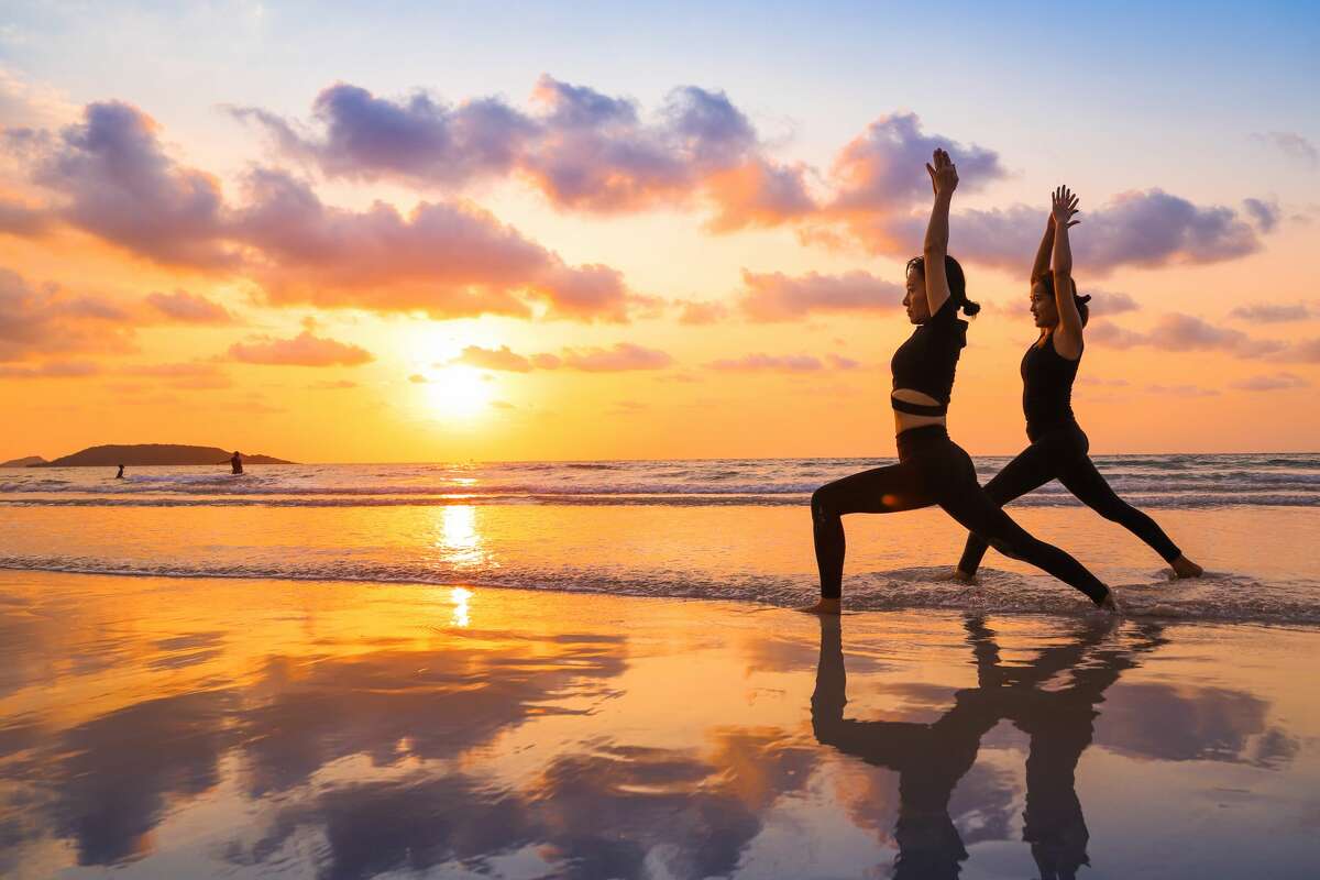 Young women practicing yoga on the beach.