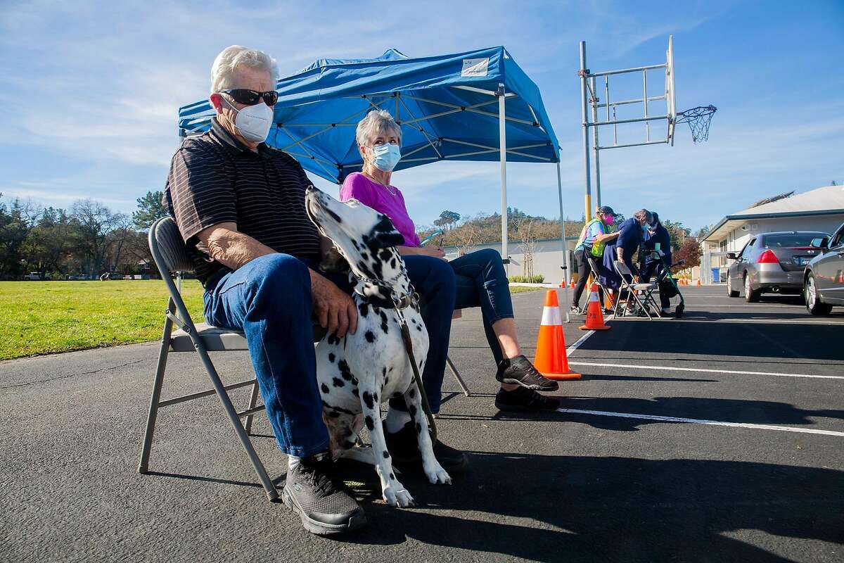 Don and Carol Franklin, 75 and 73, wait 30 minutes during post-vaccination observation alongside their dog, Ace, at the Stanley Middle School parking lot in Lafayette.