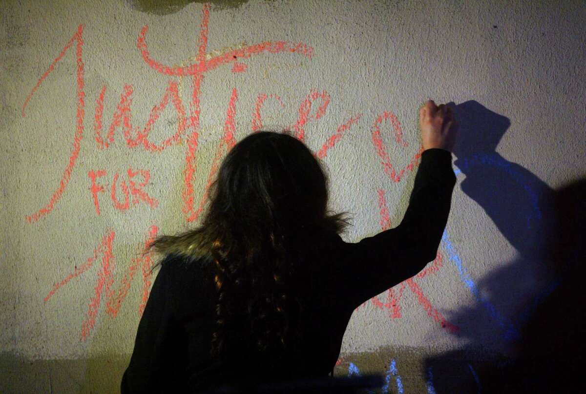 Mariam Khan draws on the wall as she attends a vigil held in memory of her friend Mubarak Soulemane at the I95 overpass along Campbell Avenue in West Haven, Conn., on Friday Jan. 15, 2021. Soulemane, a New Haven resident, was fatally shot by state Trooper Brian North after a car chase on Jan. 15, 2020.