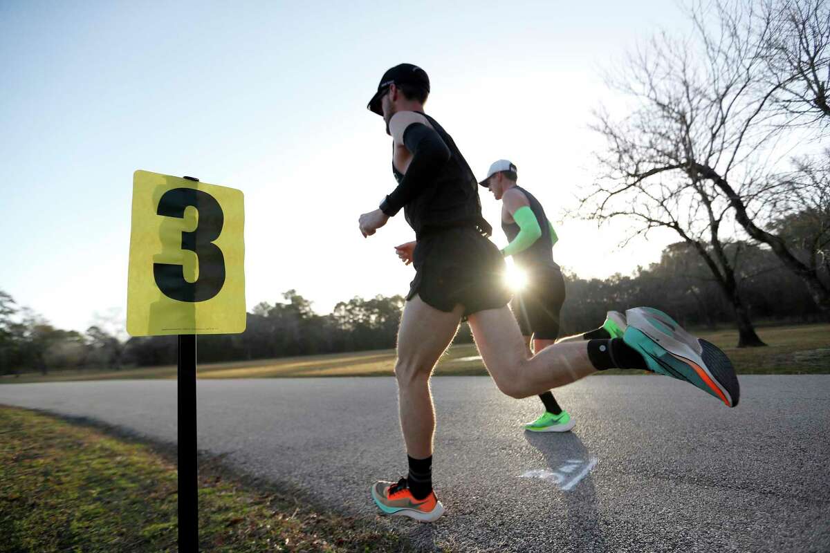 Runners pass a mile marker on a loop during an in-person 50K race at Bear Creek Park, in Houston, Sunday, Jan. 17, 2021. Eighteen of Houston's most elite runners will be participating in the run. Many are running the virtual Houston Marathon, but five women are attempting to qualify for Team USA in the marathon distance. Callum Neff, unofficial race organizer and run coach, will attempt to break the Canadian record for the 50K (31 miles) distance that was set in February 1991, in Houston.