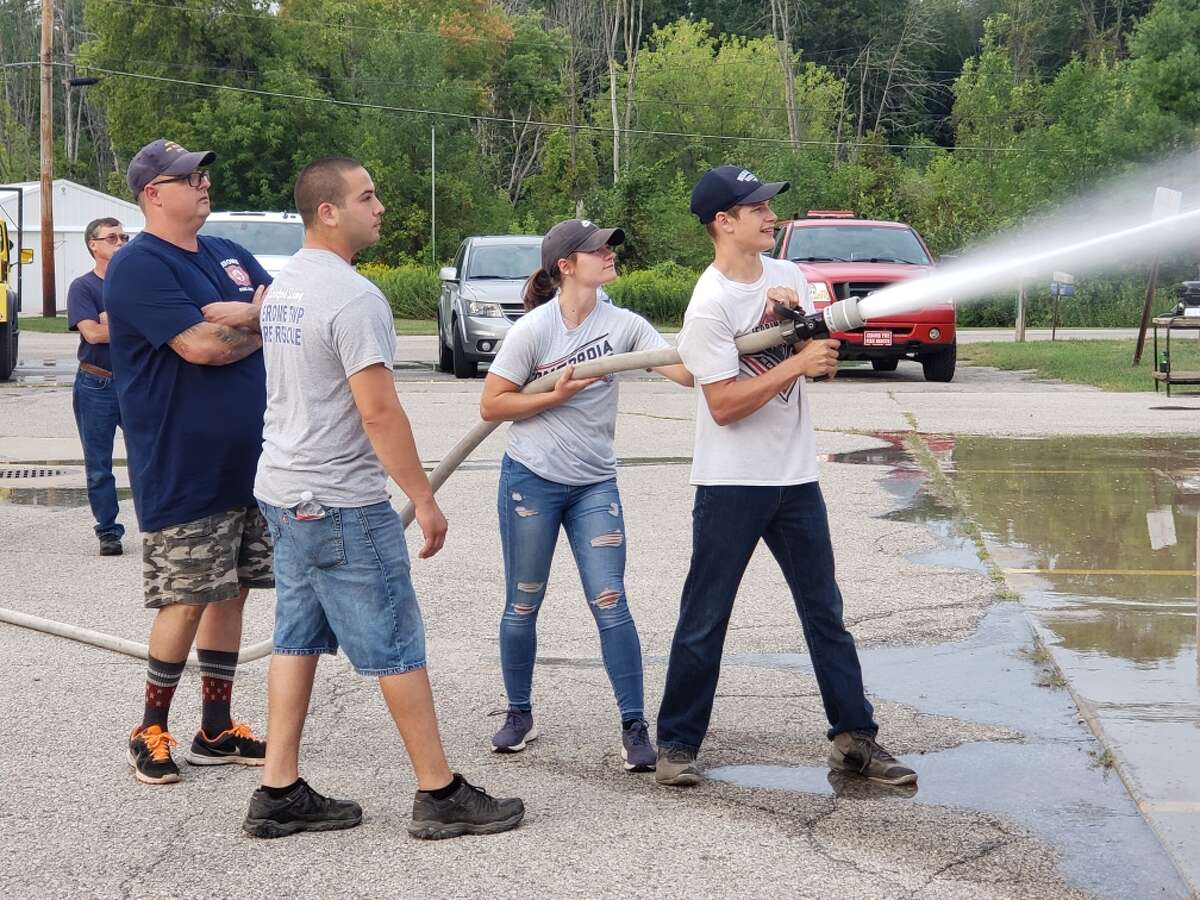 Alex Goodson and Carolina Kern, Jerome Township Fire Department's first two cadets, use a fire hose to clean off the fire station in Sanford. (Photo provided/Jerry Cole)
