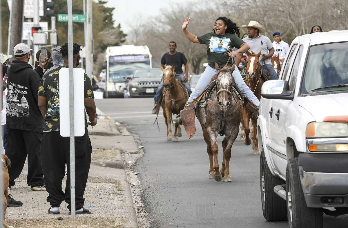 Skyy Wilson, 17, rides her horse "App" and waves to people as she rides down Martin Luther King Boulevard on Monday, Jan. 18, 2021, in Houston.