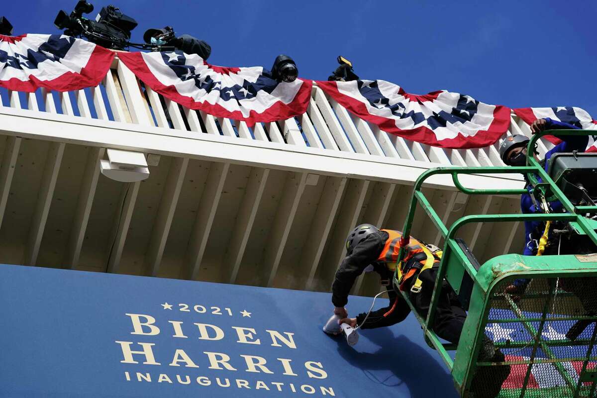 Unos trabajadores instalan unos banderines afuera de la Casa Blanca el lunes 18 de enero de 2021, en Washington, durante los preparativos para la ceremonia de investidura del presidente electo Joe Biden y de la vicepresidenta electa Kamala Harris.