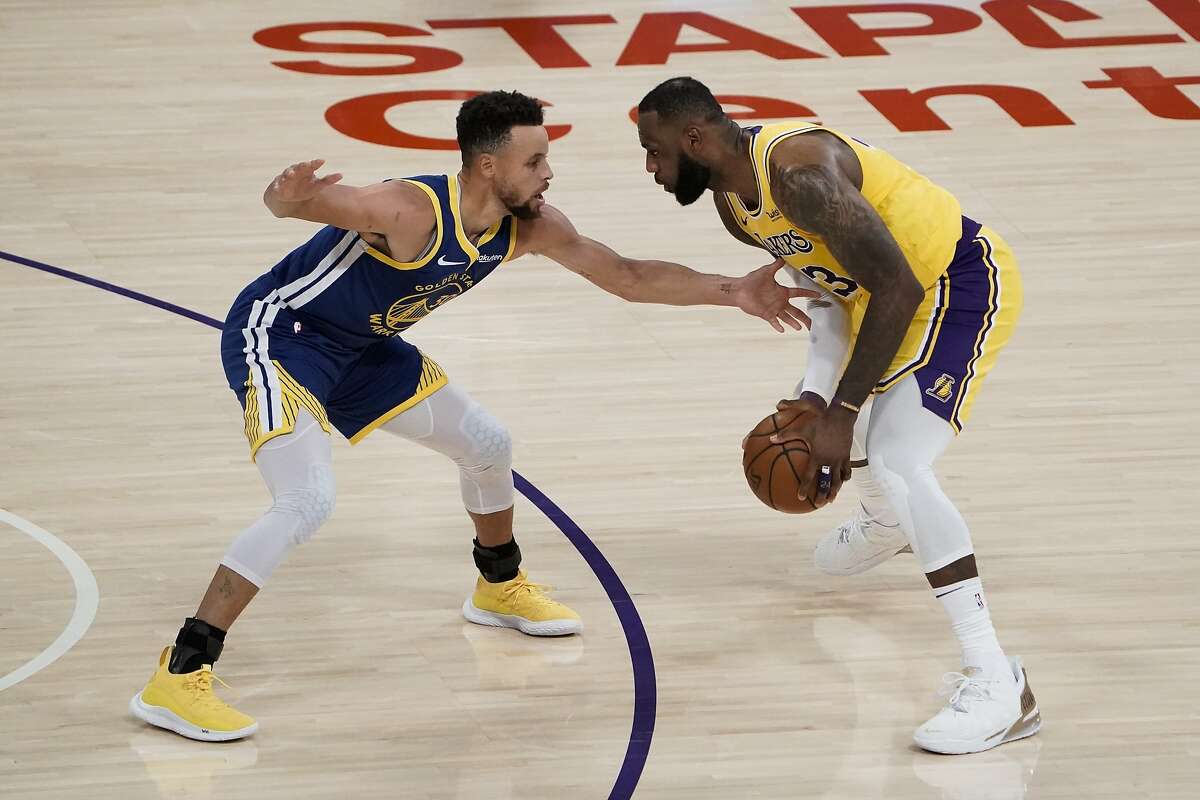 Golden State Warriors' Stephen Curry, left, pressures Los Angeles Lakers' LeBron James during the first half of an NBA basketball game, Monday, Jan. 18, 2021, in Los Angeles.