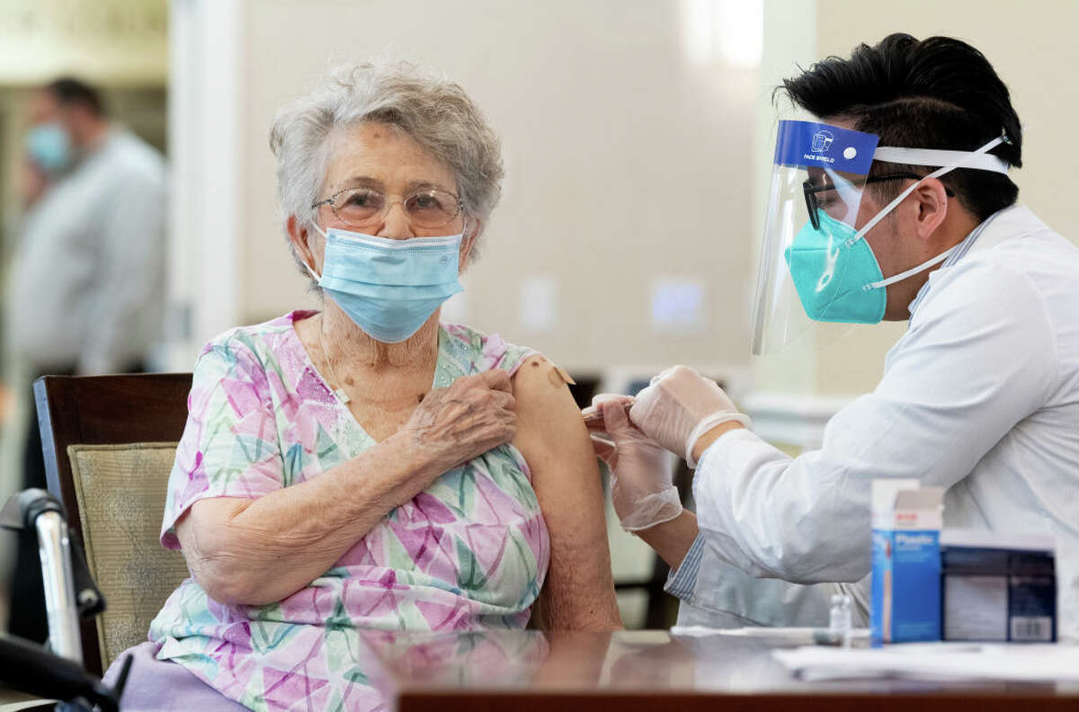 A CVS pharmacist gives the Pfizer/BioNTech COVID-19 vaccine to a resident at the Emerald Court senior living community in Anaheim, Calif., on Friday, Jan. 8, 2021.