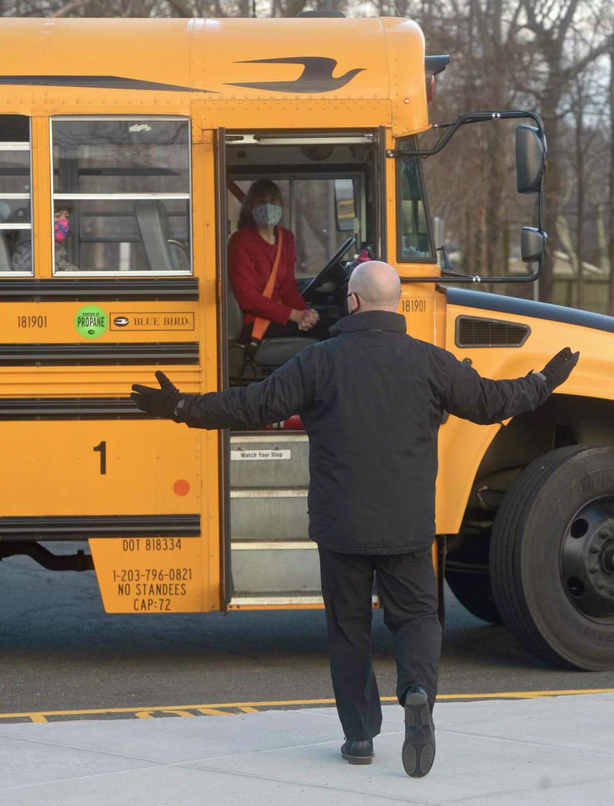 Stadley Rough Elementary School Principal Lenny Cerlich welcomes students and their bus driver back to school for the first time since March of last year. Tuesday, January 19, 2021, in Danbury, Conn.