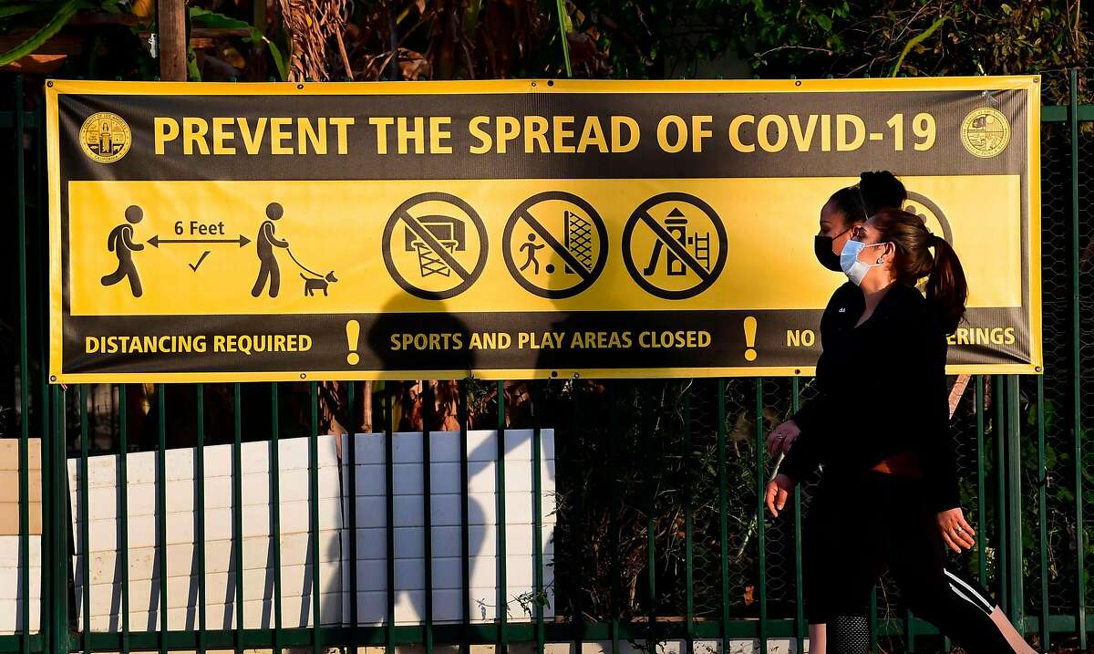 Pedestrians wearing face masks walk past a prevent the spread of Covid-19 banner in Los Angeles in January.