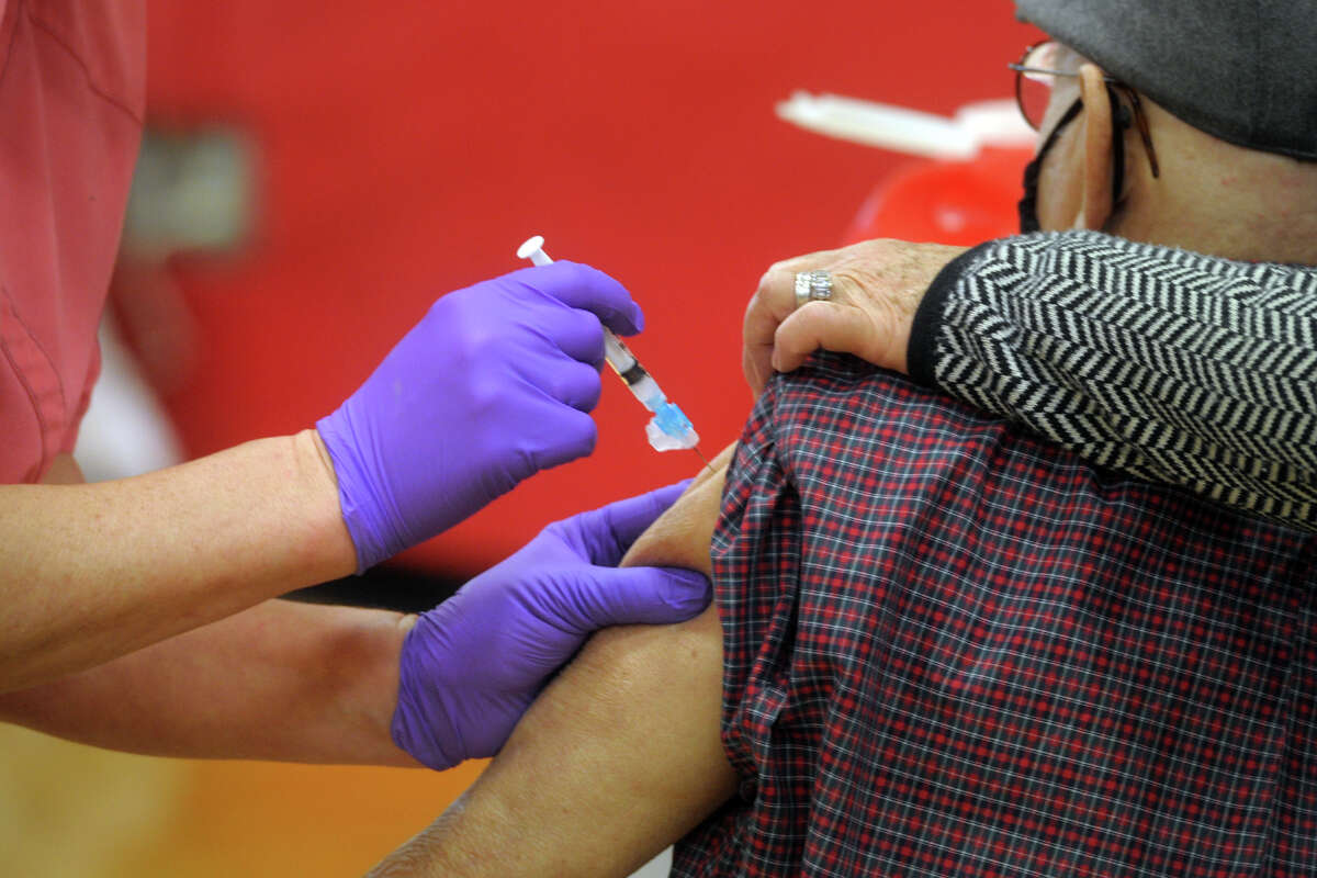 A nurse delivers a shot of COVID-19 vaccine into the arm of a patient at the new vaccination clinic set up in the gymnasium of Central High School, in Bridgeport, Conn. Jan. 20, 2021.