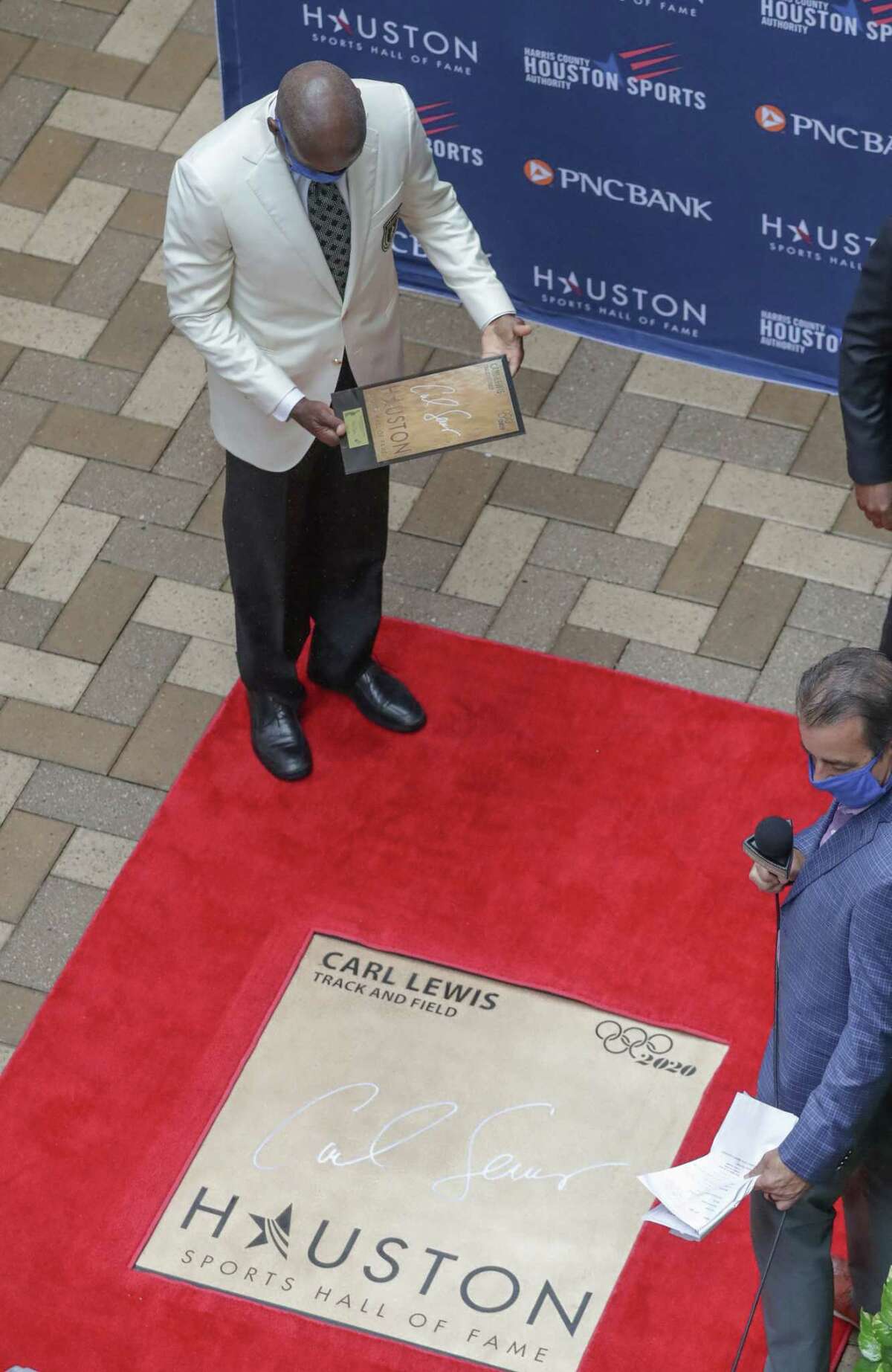 Carl Lewis looks at his walk of fame plaque during the Houston Sports Hall of Fame Ring Presentation and Walk of Fame Unveiling Thursday, Jan. 21, 2021, in Houston. Lewis, Mary Lou Retton, Rudy Tomjanovich and the late Bob Lanier were honored at the event.