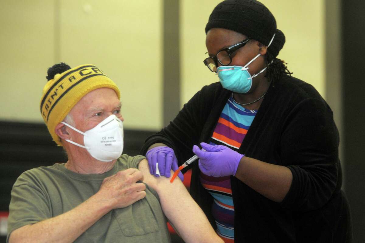 Bob Coogan, of Wilton, receives a shot of COVID-19 vaccine from nurse Martine Bristhole at the new vaccination clinic set up in the gymnasium of Central High School, in Bridgeport, Conn. Jan. 20, 2021.