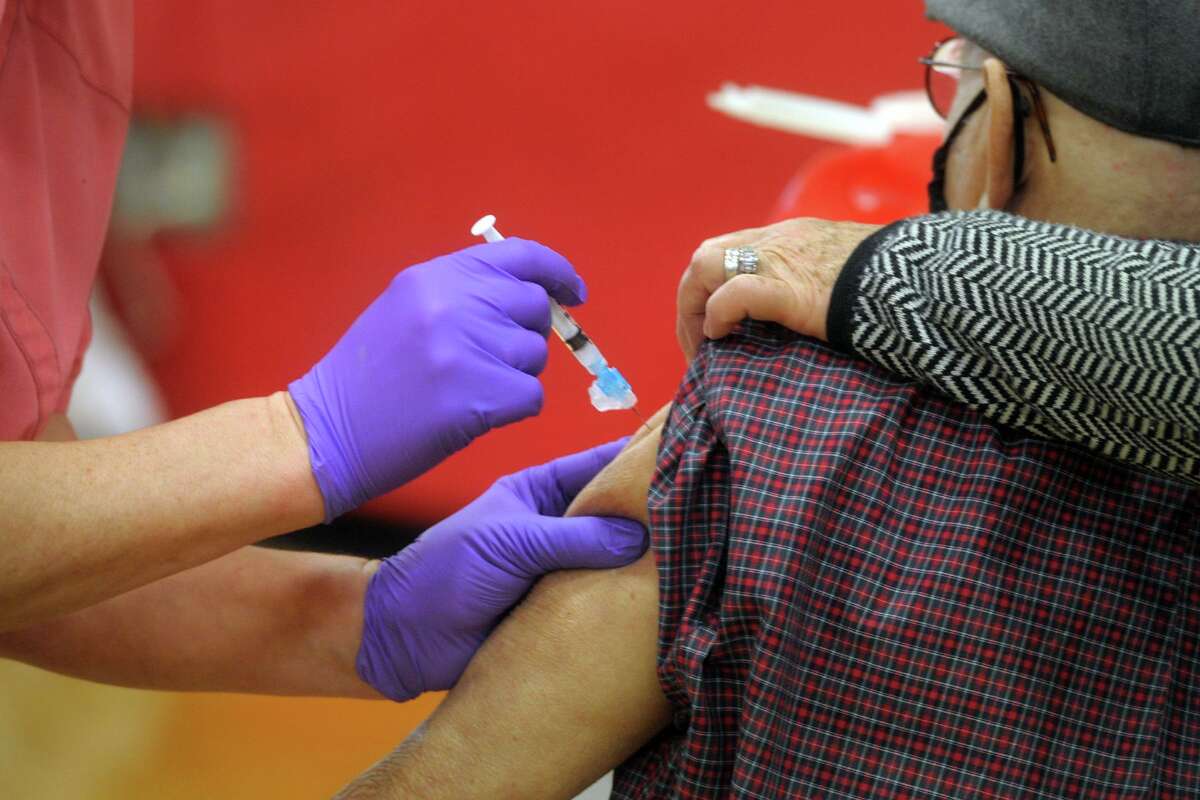 A nurse delivers a shot of COVID-19 vaccine into the arm of a patient at the new vaccination clinic set up in the gymnasium of Central High School, in Bridgeport, Conn. Jan. 20, 2021.
