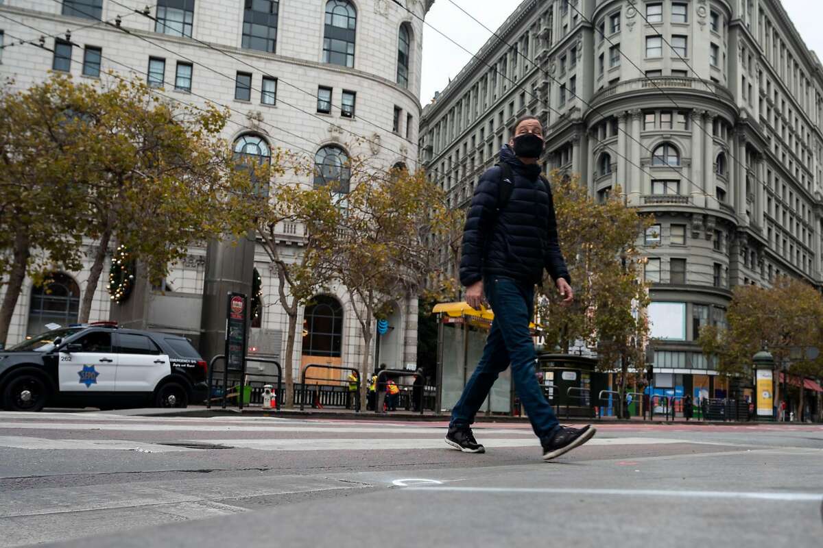 A pedestrian crosses Market Street at 5th Street on Friday, Nov. 13, 2020 in San Francisco.