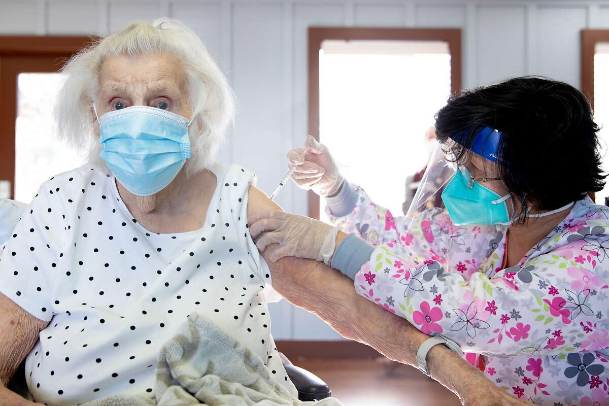 Edna Buel, 103, gets her first dose of the coronavirus vaccine from Rose Cheng while at her assisted living facility in Alameda.