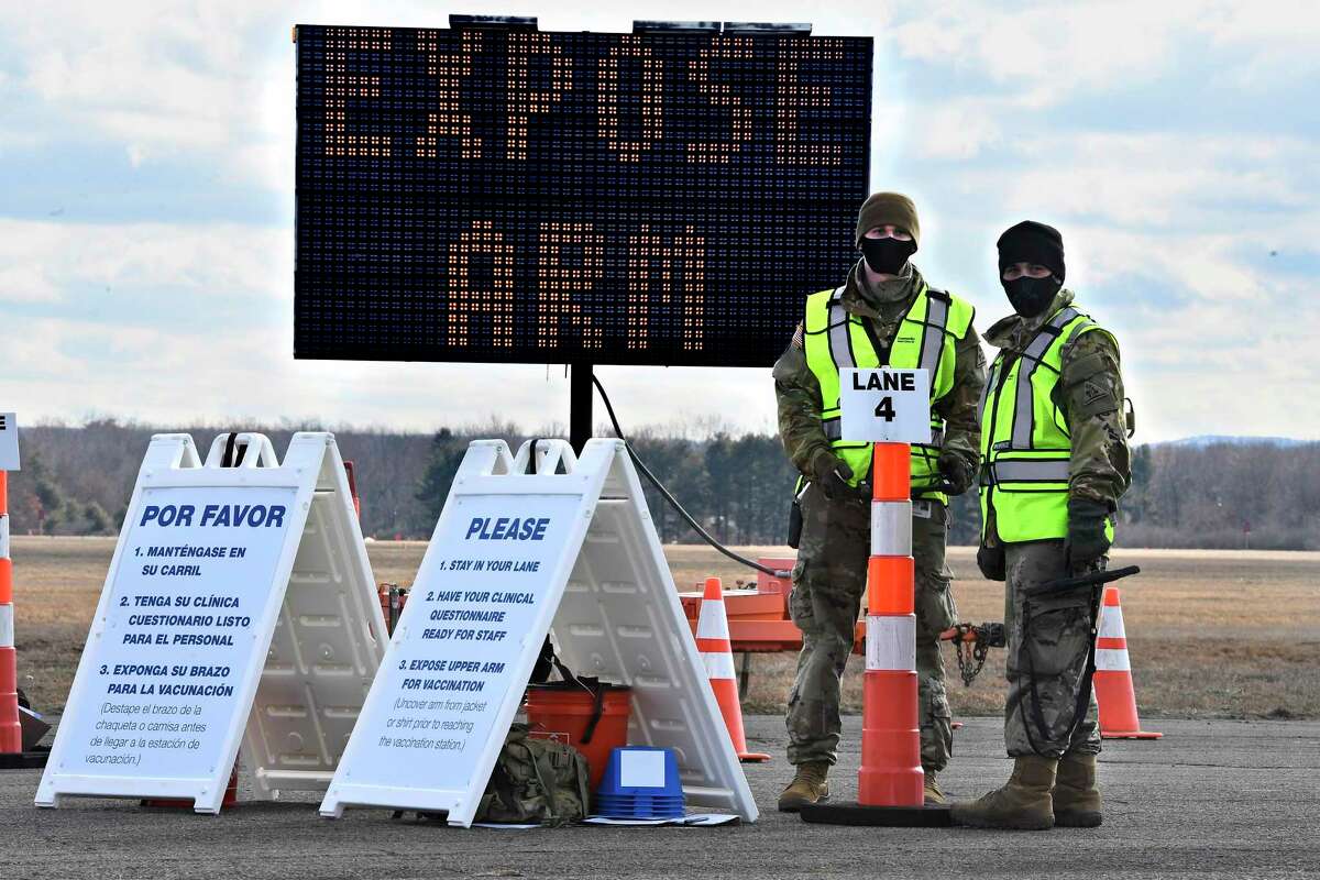 FILE - In this Jan. 18, 2021, file photo, Connecticut National Guard members wait to check-in vehicles for Connecticut's largest COVID-19 Vaccination Drive-Through Clinic in East Hartford, Conn. The push to inoculate Americans against the coronavirus is hitting a roadblock: A number of states are reporting they are running out of vaccine, and tens of thousands of people who managed to get appointments for a first dose are seeing them canceled. (AP Photo/Jessica Hill)