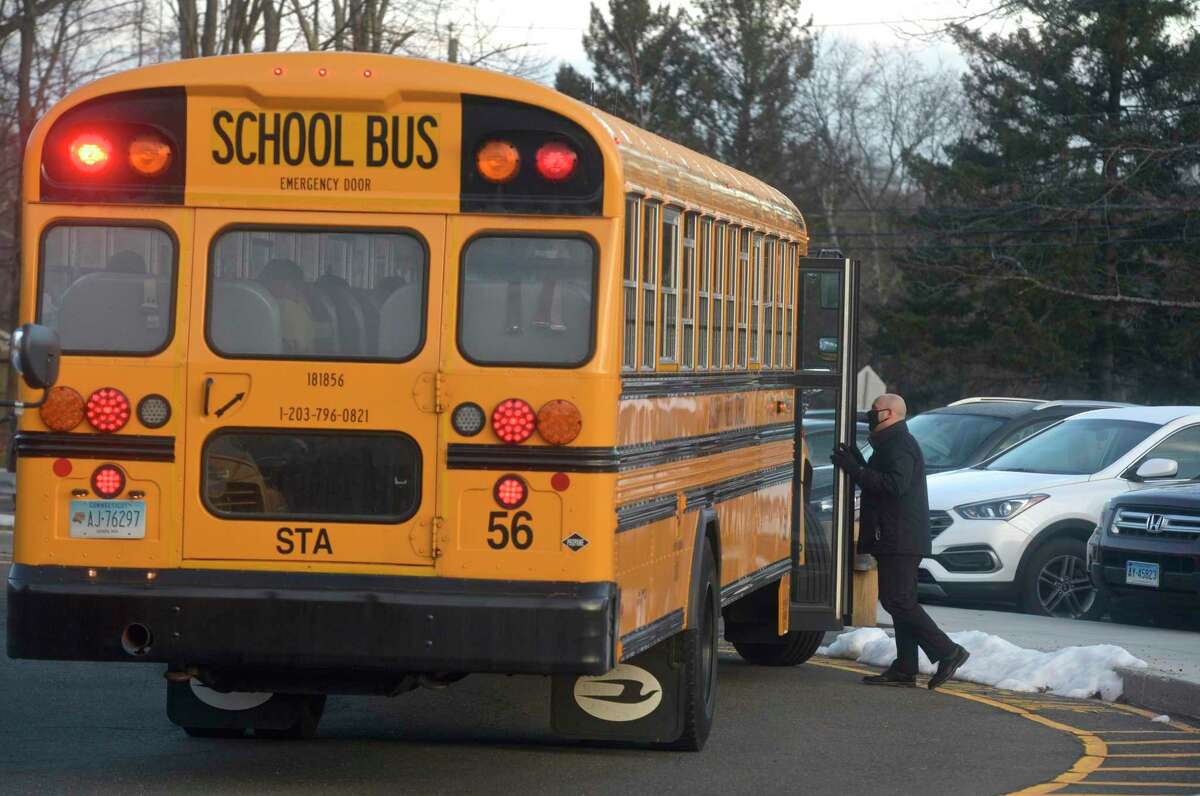 Stadley Rough Elementary School principal Lenny Cerlich welcomes students and their bus driver back to school for the first time since March of last year. Tuesday, January 19, 2021, in Danbury, Conn.