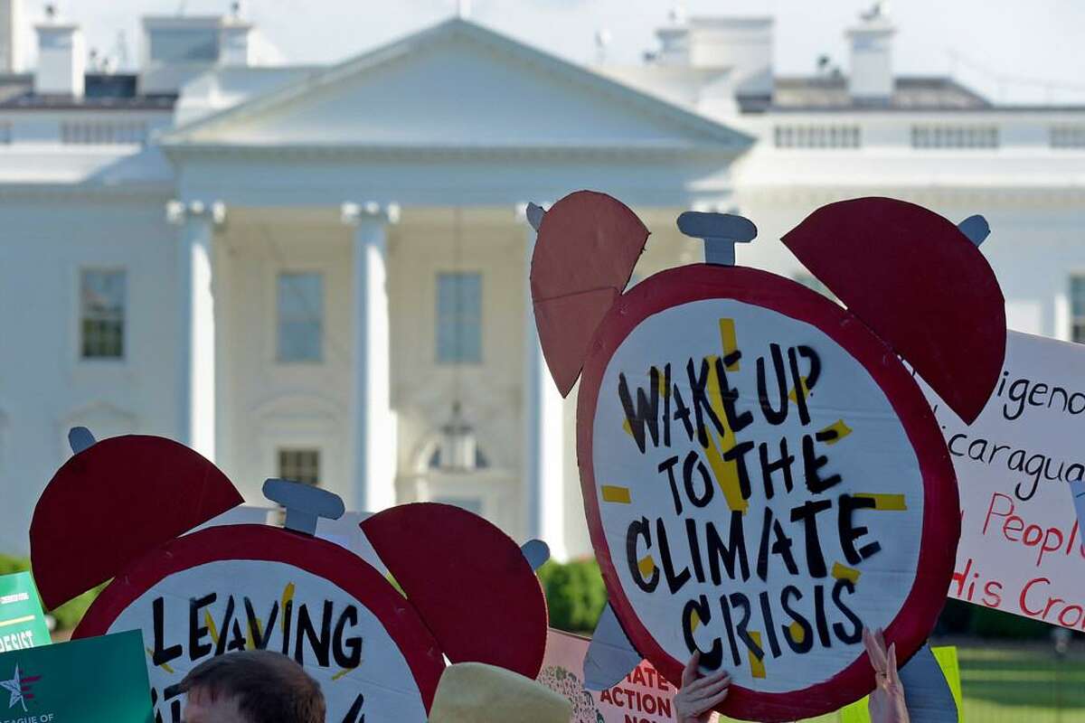 In this June 1, 2017 file photo, protesters gather outside the White House in Washington to protest President Donald Trump's decision to withdraw the Unites States from the Paris climate change accord. The Democratic-controlled House has approved legislation that would prevent President Donald Trump from following through on his pledge to withdraw the U.S. from a landmark global climate agreement.