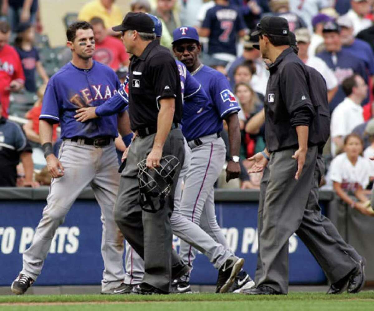 Texas' Michael Young (left) is held back by third base coach Dave Anderson (obscured) after being called out by third base umpire Alfonso Marquez (front right) to end the game.