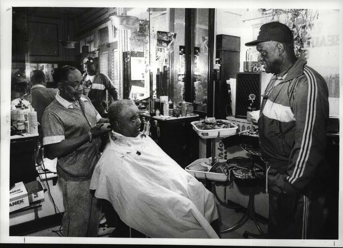 Bob Adkins, owner of the Wisteria Barber Shop at 323 S. Pearl St. in Albany, cuts Ernest Johnson's hair as Edsall Walker visits on June 21, 1990 (Paul Kniskern/Times Union Archive)