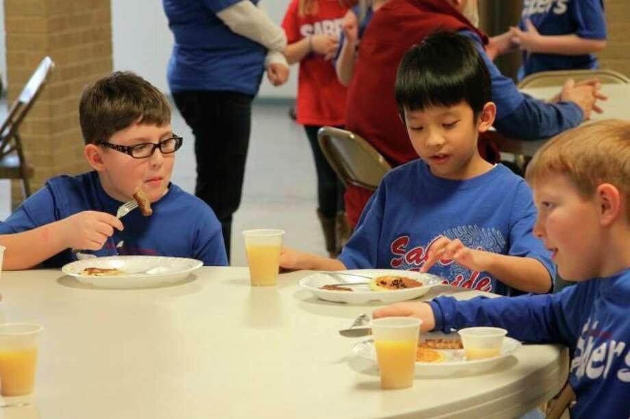 These three Manistee Catholic Central Elementary School students enjoy the pancake lunch that was prepared for the entire school by the Divine Mercy Men's Club as part of Catholic Schools week in 2018, an annual tradition. (File photo)