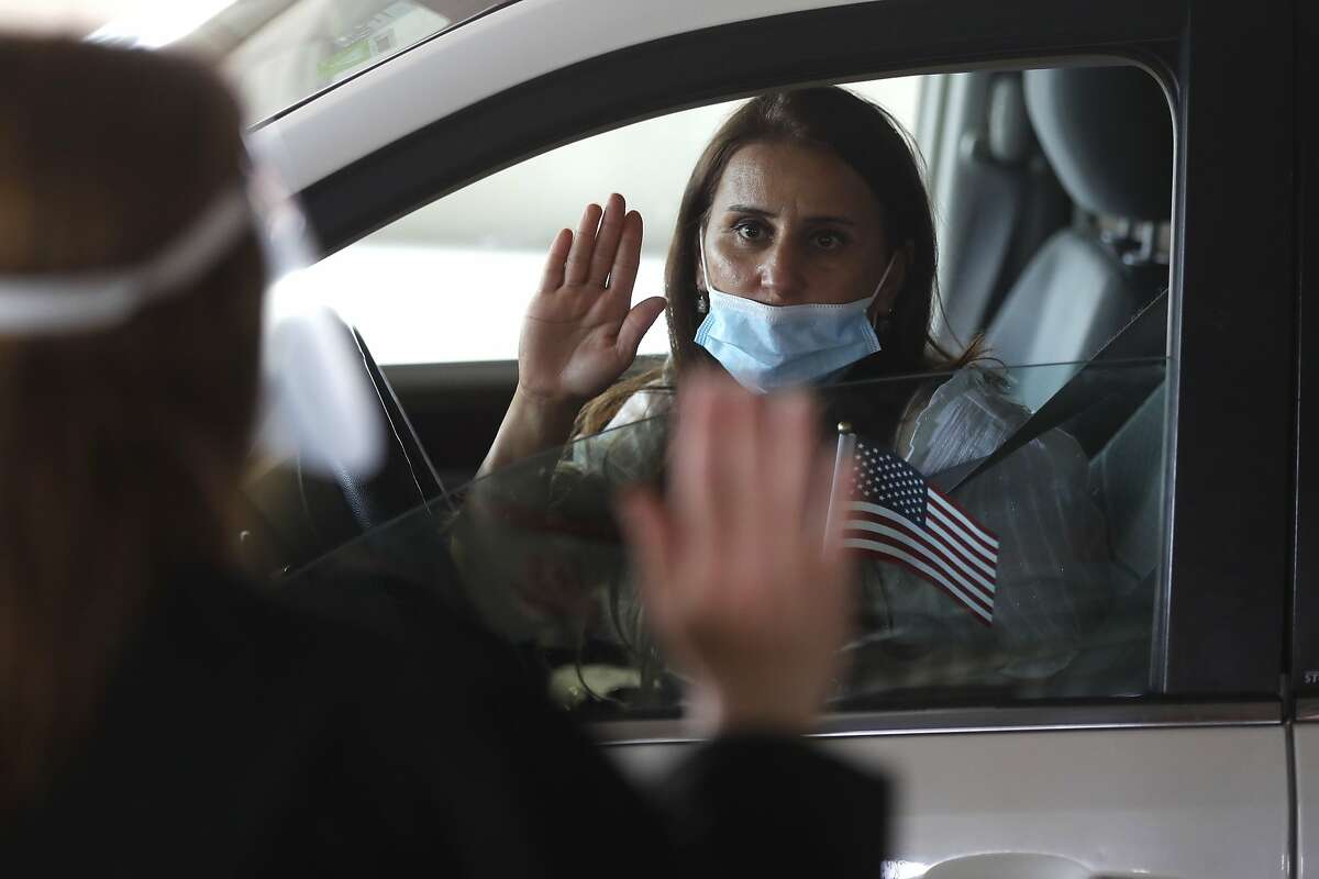 FILE- In this June 26, 2020, file photo, A U.S. district judge administers the oath of citizenship to Hala Baqtar during a drive-thru naturalization service in a parking structure at the U.S. Citizenship and Immigration Services Detroit office last June.
