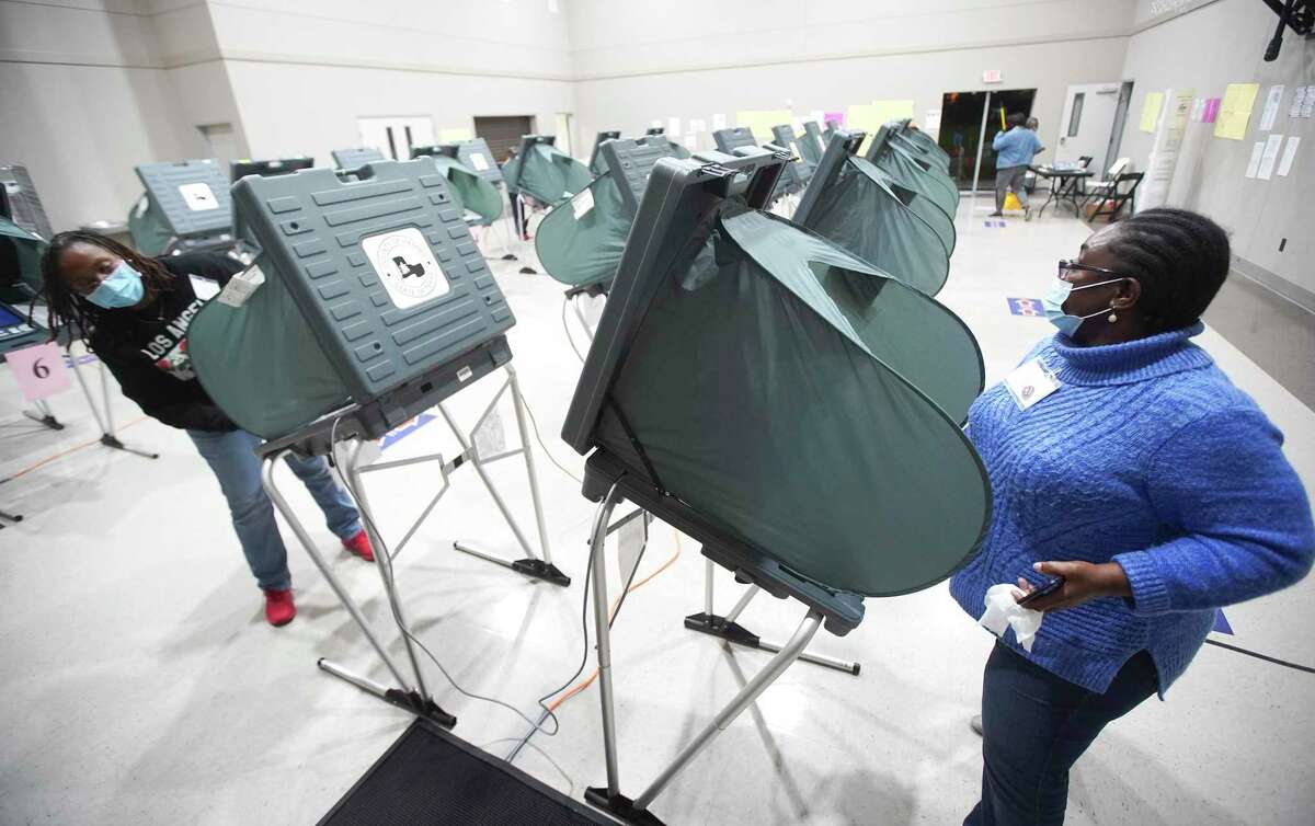 Poll workers wipe down voting machines at Victory Houston polling station in Houston on Thursday, Oct. 29, 2020. The location was one of the Harris County's 24-hour locations.