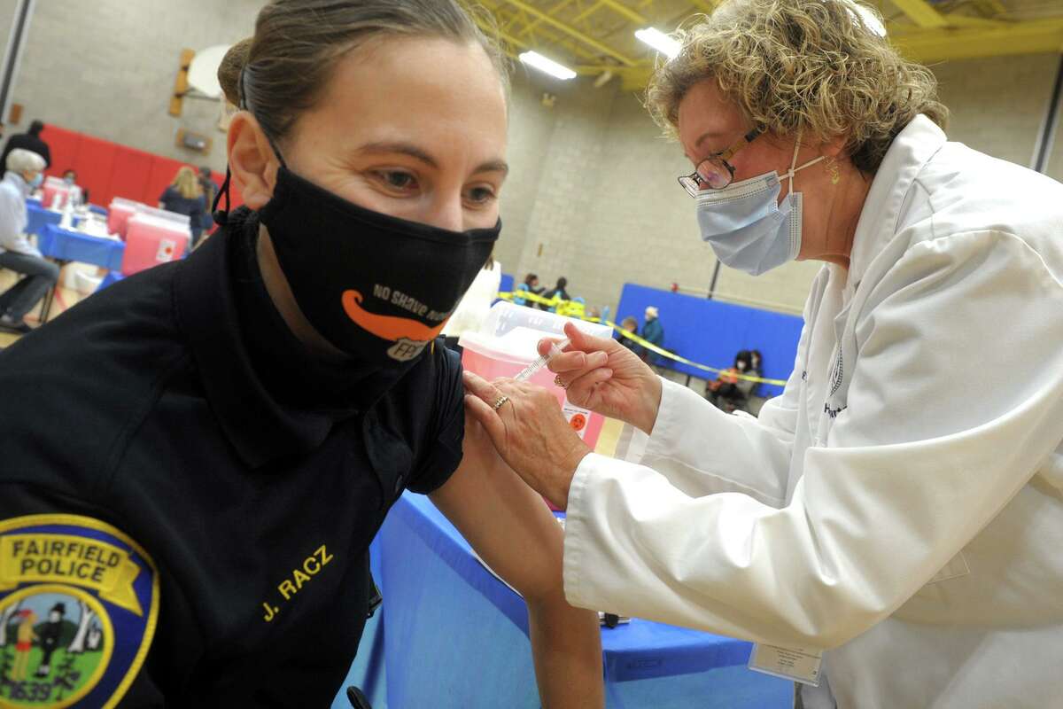 Fairfield police officer Jenna Racz receives a shot of COVID-19 vaccine from nurse Denise Gilbane at the vaccination clinic set up in the gymnasium of the Bigelow Center for Senior Activities, in Fairfield, Conn. Jan. 27, 2021.