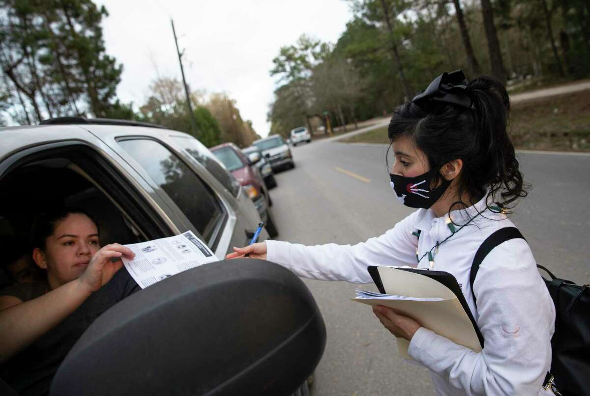 Volunteer Adilene Ramirez hands out fliers with information about COVID-19 and the vaccine to people who show up for a weekly food distribution Monday, Jan. 18, 2021, in New Caney. Texas Familias Council put in efforts to encourage Latinos, many of whom showed up for the food distribution, to get vaccinated and distribute accurate information about the pandemic amid some skepticism and misinformation about the coronavirus.