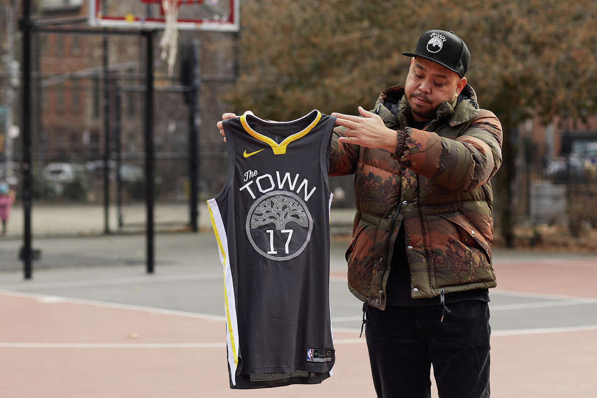 Designer and artist Dustin Canalin holding a Golden State Warriors' The Town jersey.