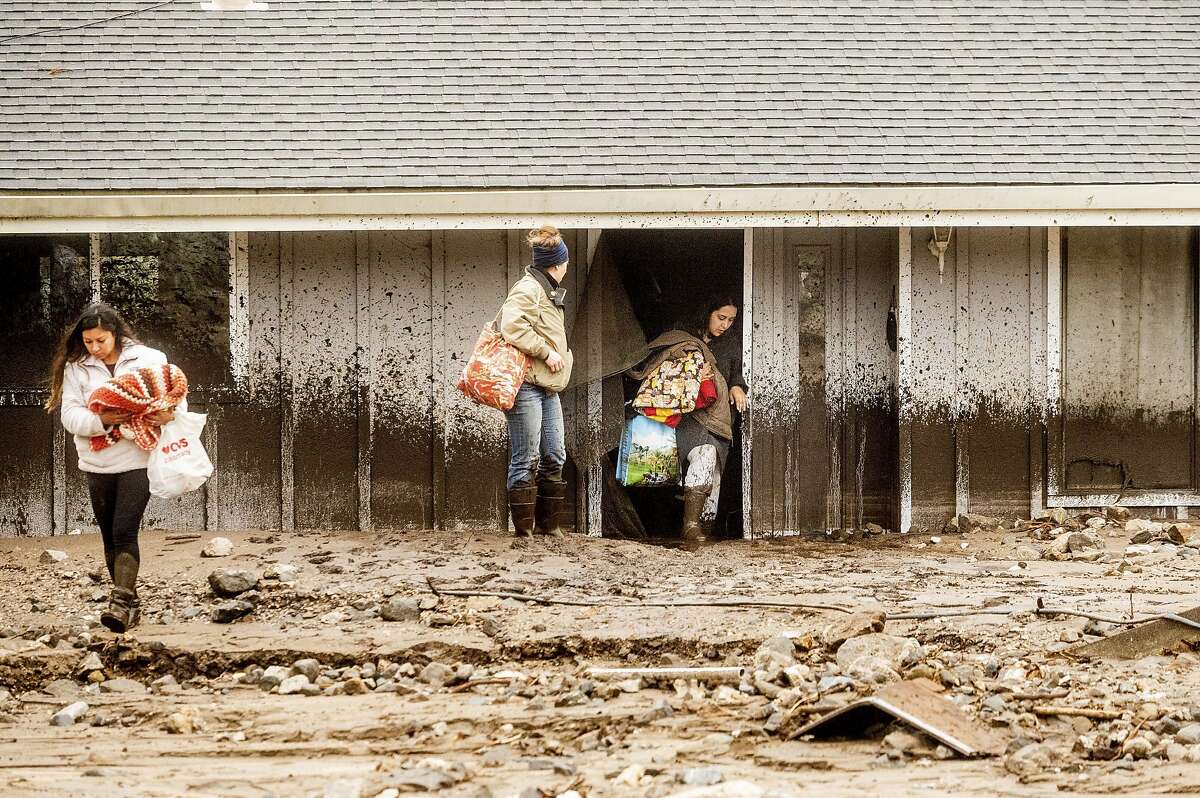 Hana Mohsin, right, carries belongings from a neighbor's home that was damaged in a mudslide on Wednesday, Jan. 27, 2021, in Salinas, Calif. The area, located beneath the River Fire burn scar, is susceptible to landslides as heavy rains hit hillsides scorched during last year's wildfires.