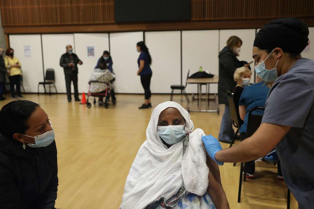 Elsa Asfaha (l tor r) of Windsor talks to her mother Mizan Tekle, 82 of Santa Rosa as Tekle receives a Pfizer COVID-19 vaccine from Tarnjit Kaur, LVN with Logistics Health Incorporated/OptumServe, during a COVID-19 vaccination clinic for senioirs 75 and over at the Rohnert Park Community Center on Wednesday, January 27, 2021 in Rohnert Park, Calif.