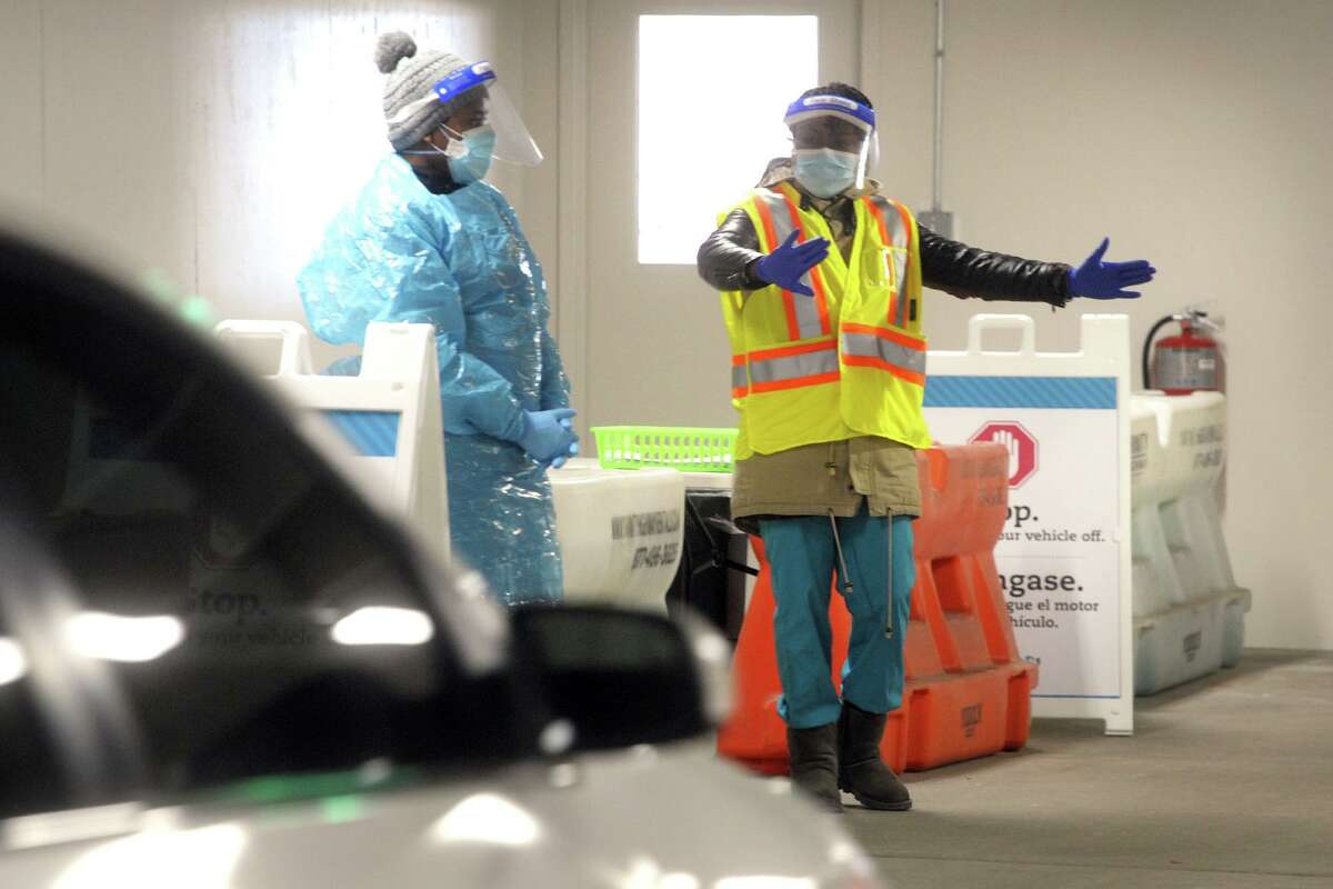Medical personnel work in Hartford HealthCare’s new drive-through COVID-19 testing sight inside the parking garage adjacent to the Arena at Harbor Yard, in Bridgeport, Conn. Jan. 25, 2021.