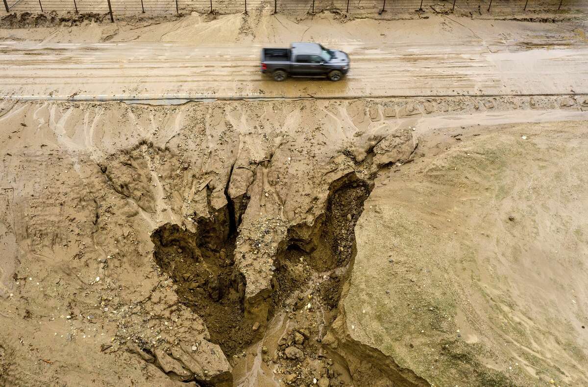 In this aerial image taken with a drone, a truck drives along River Road on Thursday, Jan. 28, 2021, where heavy rains caused mudslides and flooding near Salinas in Monterey County, Calif. The area sits beneath hillsides scorched in last year's River Fire.