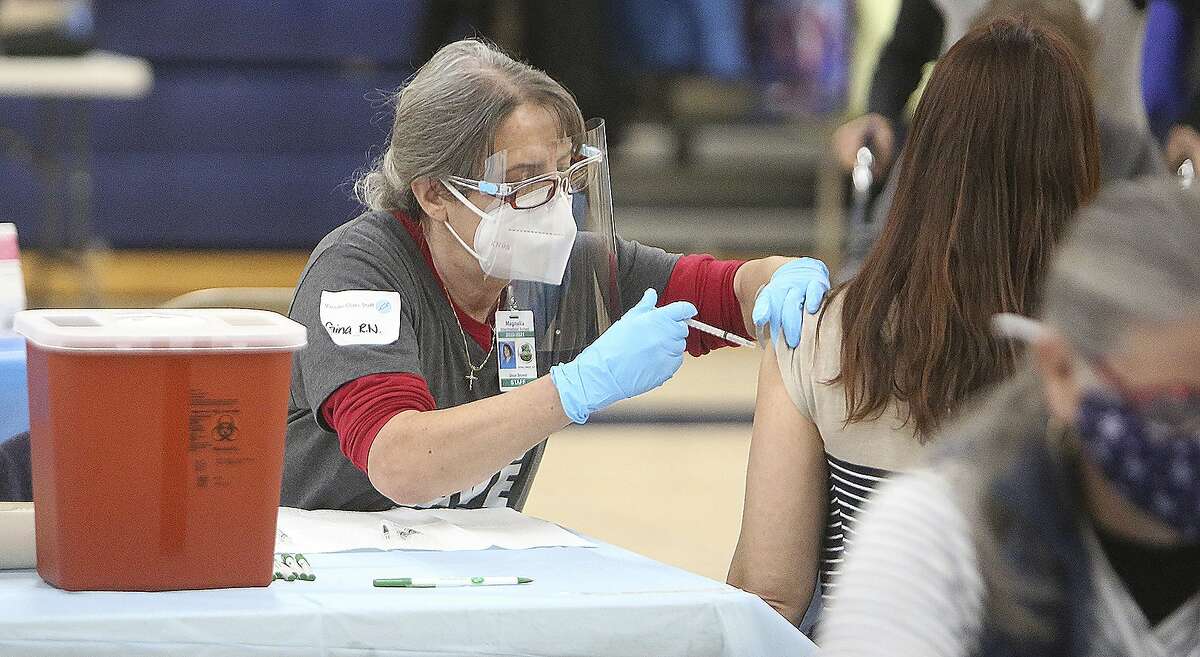 Pleasant Ridge School Nurse Gina Shield administers a coronavirus vaccine on to a school employee on the gymnasium floor at Nevada Union High School in Grass Valley (Nevada County).
