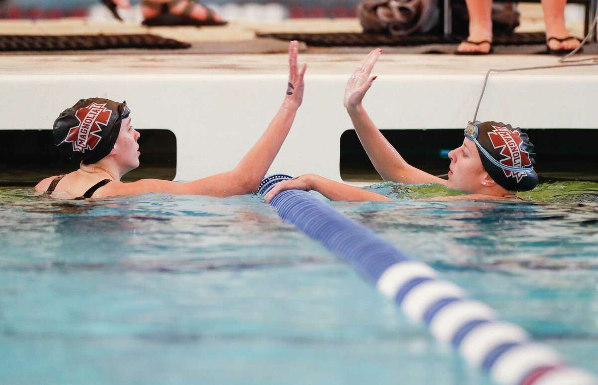 Presley Heitzmann of Magnolia, left, gives teammate Claire Culberson a high-five after competing in the girls 100-yard breaststroke during the District 21-5A Swimming and Diving Championships at the Conroe ISD Natatorium, Friday, Jan. 29, 2021, in Shenandoah.