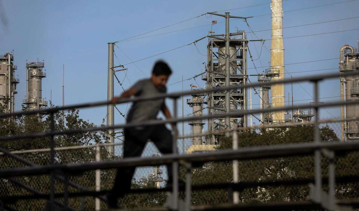 The Valero Houston Refinery is seen in the background as a child climbs on bleachers Wednesday, Jan. 27, 2021, at Hartman Park in Houston.