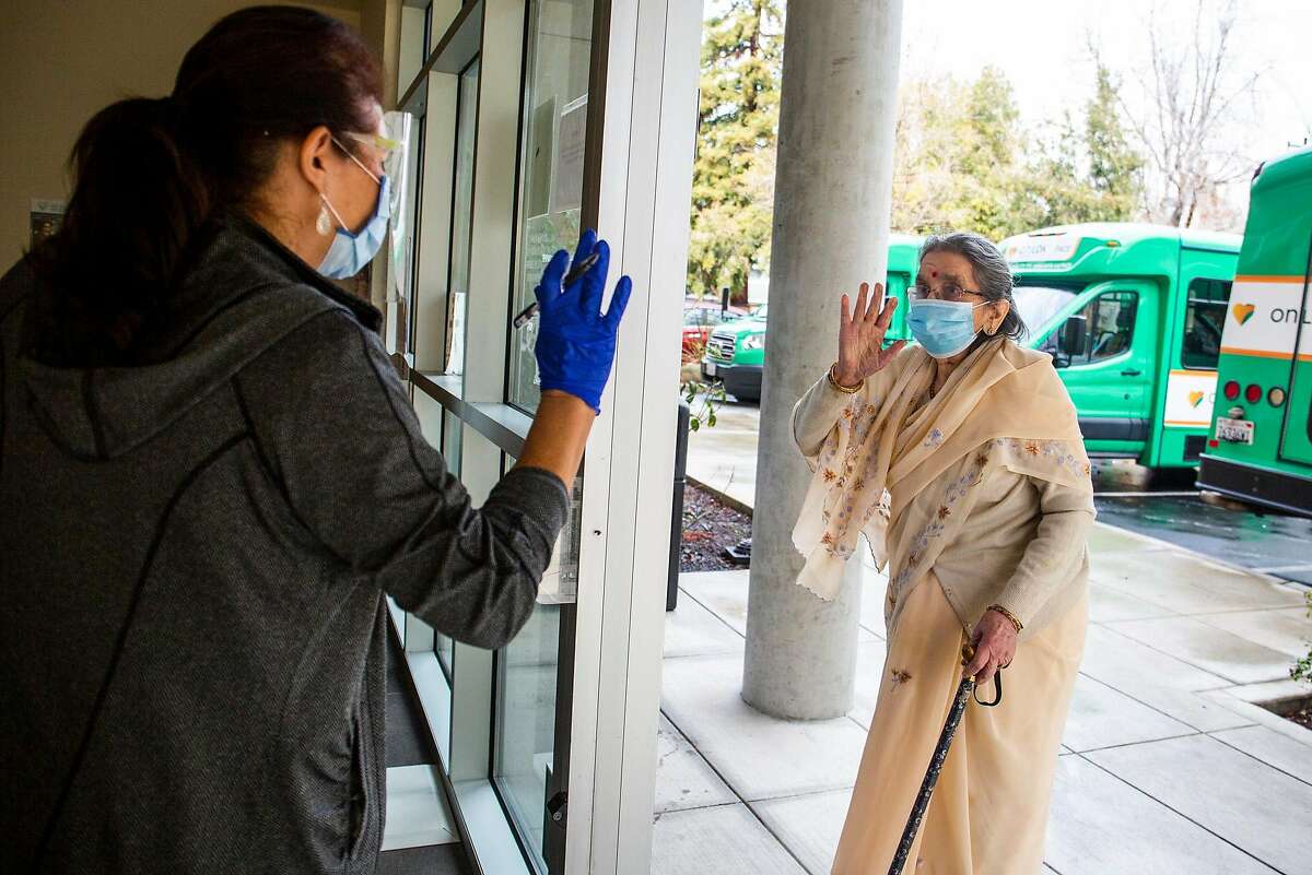 Devi Kamala, a Fremont local, waves hello to a caregiver at On Lok Pace Senior Center on her way to recieve her COVID-19 vaccine on Janurary 28, 2021.