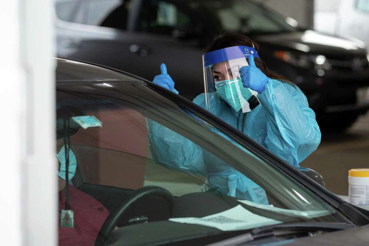 Livier Silva, a medical assistant, waves to a motorist who received a dose of the COVID-19 Moderna vaccine at the drive-through site located at Delmar Stadium on Friday, January 29, 2021, in Houston.  The site is operated in a partnership between the city and United Memorial Medical Center.